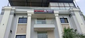 a tall white building with a sign on it at Accuotel Hotel Perfect in Indore