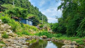 a river with rocks and houses next to a mountain at Pocheon Arumdri Pension in Pocheon