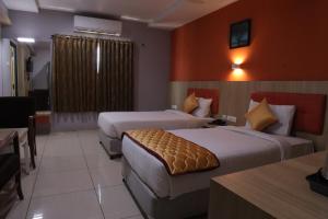 a hotel room with two beds and a table at PLA RESIDENCY Trichy near Rockfort Temple in Tiruchirappalli +34 photos