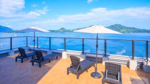 a deck on a cruise ship with chairs and an umbrella at Livemax Resort Mihara Onsen Seafront in Mihara