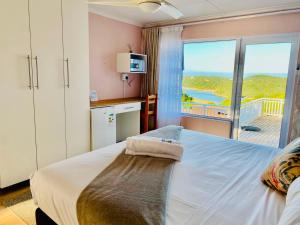 a bedroom with a large bed with a view of the ocean at Clearview Estuary Apartments in East London
