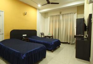 a hotel room with two beds and a flat screen tv at Hotel Bluemoon in Guwahati +16 photos