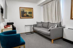 a living room with a gray couch and a blue chair at The Square Hotel in Cluj-Napoca