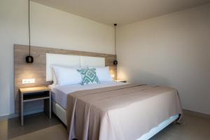 a bedroom with a large white bed and a side table at Amaltheia Beachfront Villas in Kypseli +96 photos