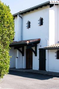 a white building with a brown door and windows at Villa des Landes - Seignosse - Jacuzzi in Seignosse