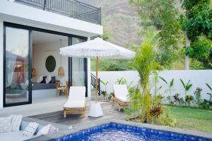 an outdoor patio with an umbrella and a swimming pool at Villa Mercure. Private villa. 2 en-suite bedrooms. in Amed