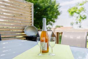 a bottle of wine and two glasses on a table at 11 - Le Rossignol - Village vacances in Maché