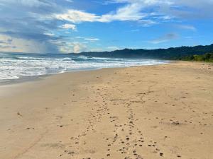 a beach with footprints in the sand and the ocean at Fresh Beach Resort in Cateel