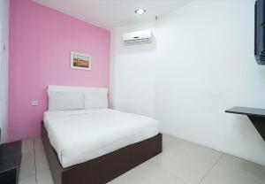 a bed in a room with a pink wall at Cahaya Midah Hotel (BilikXpert) in Kuala Lumpur