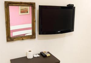 a tv on a wall with two remote controls and a table at Cahaya Midah Hotel (BilikXpert) in Kuala Lumpur
