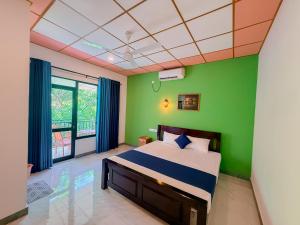 a bedroom with a bed with a green wall at Deer Inn - Yala in Tissamaharama