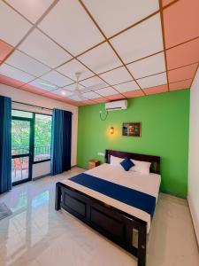 a bedroom with a bed with a green wall at Deer Inn - Yala in Tissamaharama