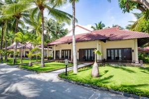 a house with palm trees in front of a street at Diamond Bay Resort & Spa in Nha Trang