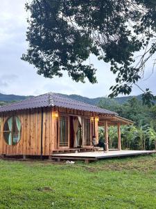 a wooden cabin with a porch in a field at zen mountain farmstay in Mae Wang