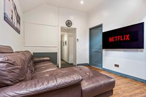 a living room with a brown leather couch and a tv at Group-Friendly, Sheffield Flat, sleeps 6 in Walkly