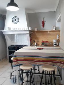 a kitchen with a counter with stools and a clock on the wall at La charmante Capbretonnaise in Capbreton