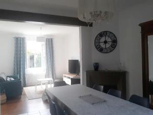 a living room with a table and a clock on the wall at La charmante Capbretonnaise in Capbreton