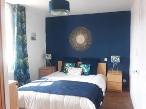 a bedroom with a bed with a blue wall at La charmante Capbretonnaise in Capbreton