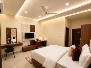 a bedroom with a large white bed and a television at Sree Durga Hotel Ramsons International in Mysore