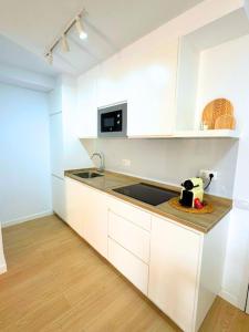 a white kitchen with a sink and a microwave at Cozy & Terrace Apartament5 in Los Cristianos