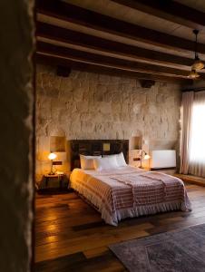 a bedroom with a bed and a stone wall at Seki Cave Hotel, Wake Up to Hot Air Balloons in Göreme