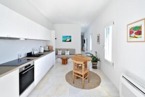 a kitchen with white cabinets and a wooden table at Theros Apartments 3 in Mylopotas