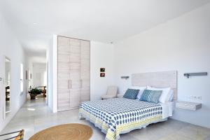 a white bedroom with a bed and a chair at Theros Apartments 3 in Mylopotas