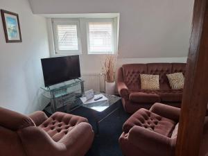 a living room with two couches and a flat screen tv at Pension Villa Maria in Karlovy Vary