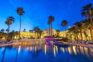 a pool with chairs and palm trees at night at SOL by Meliá Lanzarote All Inclusive in Puerto del Carmen +44 photos