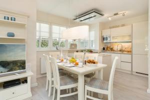 a white kitchen with a white table and chairs at Ferienhäuser TraumZeit in Zingst