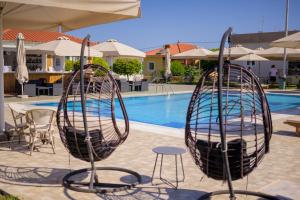 a swimming pool with two chairs and a table and an umbrella at Stomio Villague in Filiatra