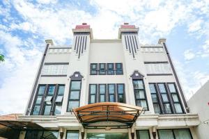 a large white building with a clock on it at Audah Syariah Residence Mitra RedDoorz in Surabaya