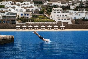 a person diving into a body of water at Mykonos Riviera Hotel & Spa, a member of Small Luxury Hotels of the World in Tourlos