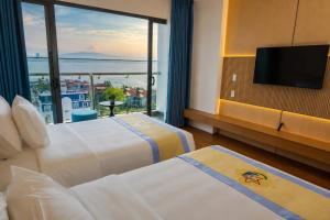 a hotel room with two beds and a large window at The Golden Crest Hotel Quy Nhon in Quy Nhon