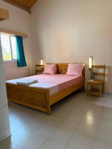 a bedroom with a large wooden bed with pink pillows at Le Clos Rivière in Ndangane +18 photos
