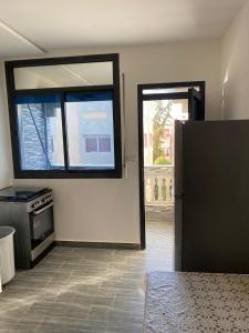 a kitchen with a refrigerator and a large window at Appartement 1 in Al Hoceïma