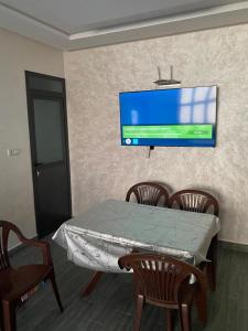 a table with chairs and a tv on a wall at Appartement 1 in Al Hoceïma