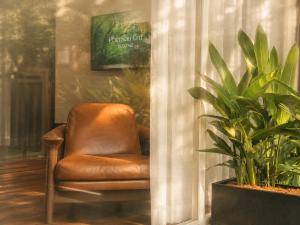 a brown chair in a room with a plant at Amana Boutique Riverside - An Khanh in Ho Chi Minh City