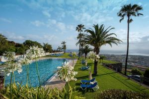 a swimming pool with palm trees and blue chairs at Hotel Las Águilas Tenerife, Affiliated by Meliá in Puerto de la Cruz