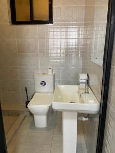 a white bathroom with a toilet and a sink at Sky Beach Resort in Kisumu