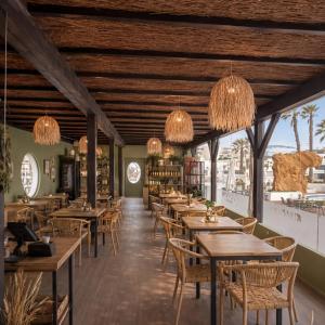 a restaurant with wooden tables and chairs and chandeliers at Sands Beach Resort in Costa Teguise
