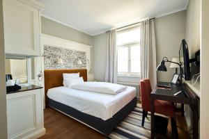 a hotel room with a bed and a desk with a computer at Hotel Halm Konstanz in Konstanz
