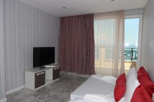 a hotel room with a bed and a flat screen tv at Golden Sea View Penthouse in Pomorie