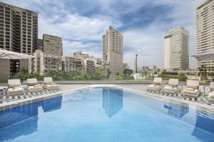 a swimming pool with lounge chairs and a city skyline at Pyramisa Suites Hotel Cairo in Cairo