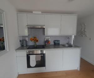 a kitchen with white cabinets and a sink at The Nook in Inverness +12 photos