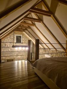 a attic room with a bed and a stone wall at Kamena kuća Goranci in Mostar