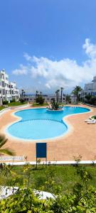 a large swimming pool on a beach with buildings at Élégant appartement de 3 chambres vue piscine n4 in M'diq