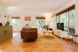 a living room with a couch and a table at River Reach Chalet - Cosy Forest Hideaway in Margaret River Town