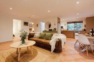 a living room with a couch and a table at River Reach Chalet - Cosy Forest Hideaway in Margaret River Town +53 photos