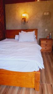 a wooden bed with white sheets and a light on the wall at Bamboo Craft Homestay in Sangyang